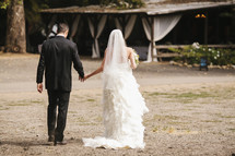 bride and groom walking hand in hand outdoors to their wedding reception