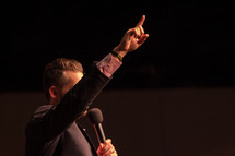 a preacher with a raised hand holding a microphone 