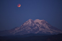blood moon over a mountain peak