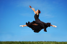 Ballerina leaping in a field of grass.