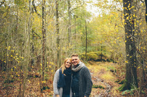 a couple standing together in a forest 