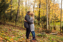 a couple kissing in a fall forest 