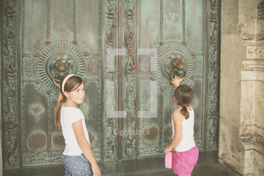 children knocking on front doors of an ancient cathedral 