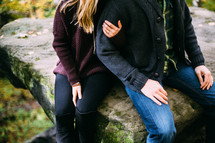 a couple sitting on rocks outdoors 