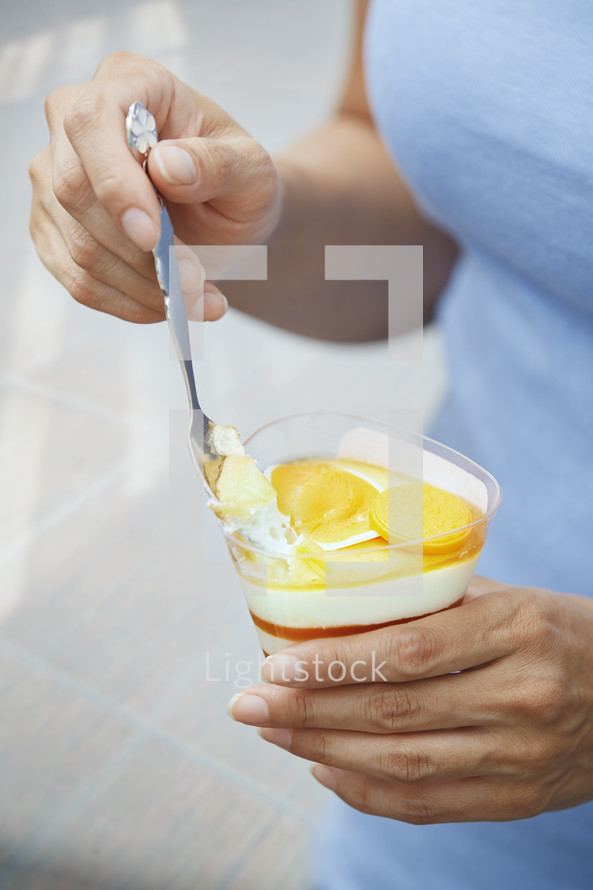 Hands of woman eating fruit mousse