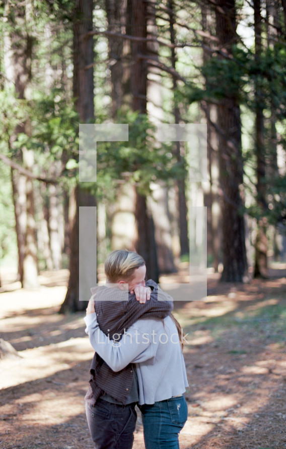 a couple hugging in the woods 
