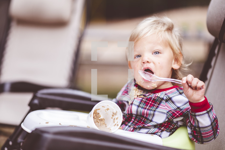 toddler eating in a makeshift high chair while camping 