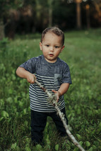 a toddler boy playing with a stick 