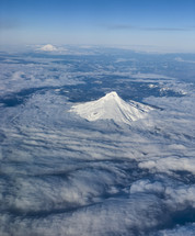 Aerial view of a snow covered mountain peak above the clouds