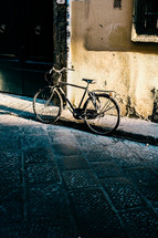 old bicycle parked along the curb of a road 