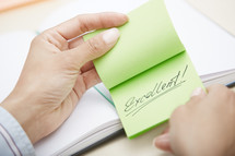 woman holding a sticky note with the word excellent 