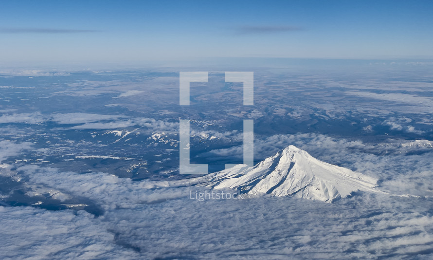 Aerial view of a snow covered mountain peak above the clouds
