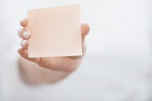 arm holding up a blank sticky note 