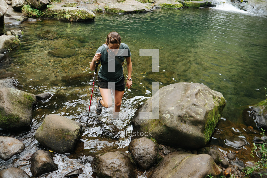 a woman hiking through a stream 