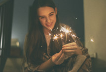 young woman sitting on stairs and lights fireworks