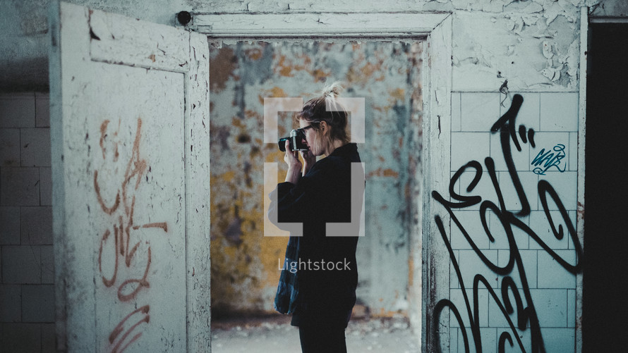 a woman taking a picture in an abandoned building covered in graffiti 