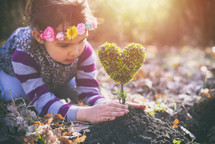 little girl planting a heart-shaped tree and dreaming of a beautiful future