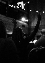 a woman at a worship service with raised hands 
