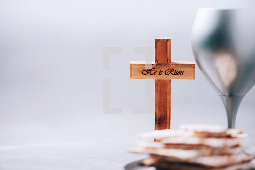 Matzos unleavened bread, chalice of wine, wooden cross on grey background. Christian communion for reminder of Jesus sacrifice. Easter passover. Eucharist concept. Christianity symbol and faith