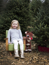 girl toddler in a chair in a Christmas tree lot 