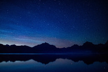 stars in the night sky over a lake 