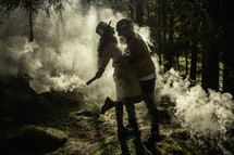 Stylized image of couple in woods with smoke
