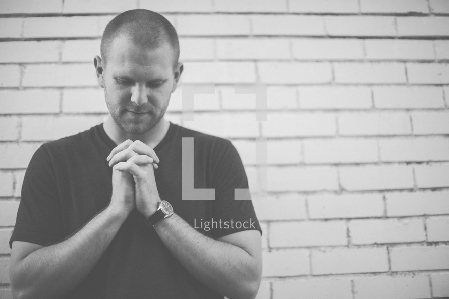 a man with praying hands and head bowed 