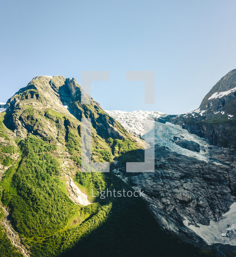 ice on cliffs and green mountainside 