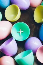 Silver cross inside colorful plastic Easter egg.