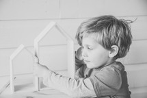 a child playing with wooden house forms 
