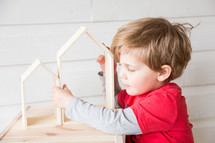 a child playing with wooden house shaped blocks 