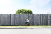 boy riding a bicycle on a sidewalk 