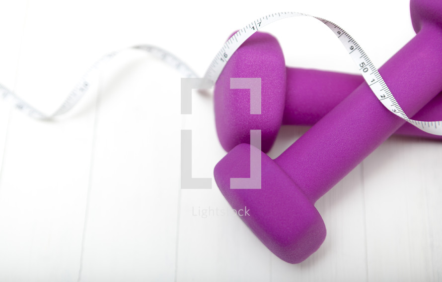 measuring tape and pink free weights 