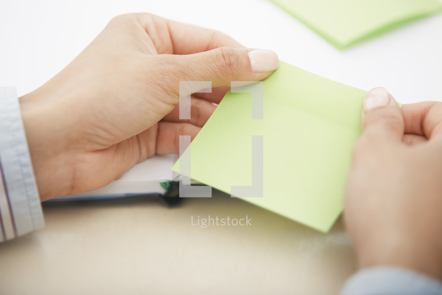 woman holding a pad of blank sticky notes 