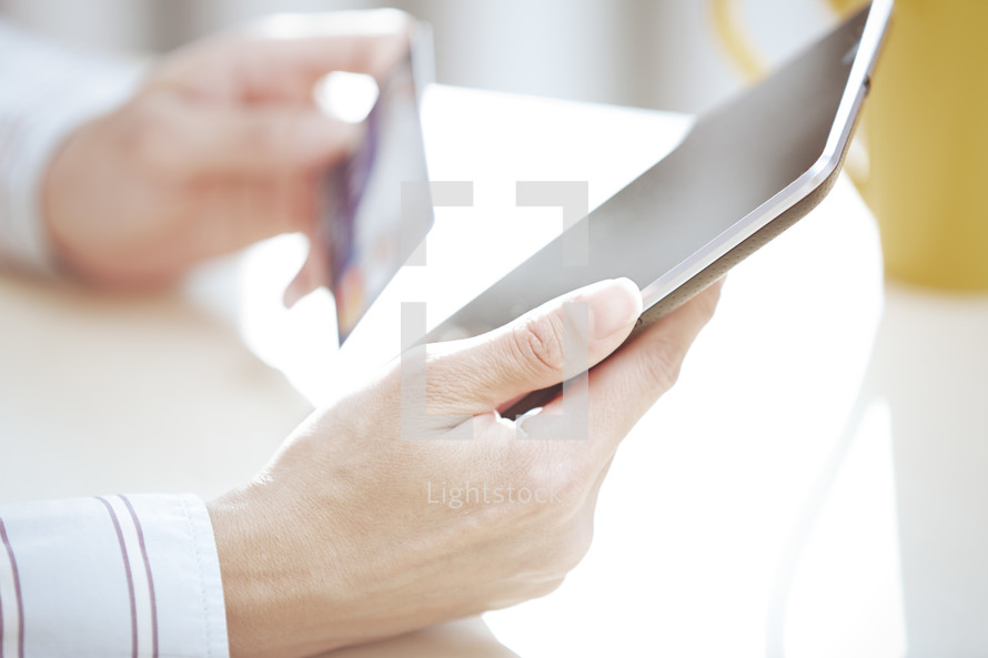 a person holding a tablet and credit card 