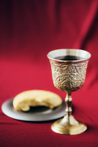 Unleavened bread, chalice of wine, silver kiddush wine cup on red background. Communion still life. Christian communion concept for reminder of Jesus sacrifice. Easter passover