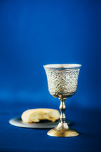 Communion still life. Unleavened bread, chalice of wine, silver kiddush wine cup on blue background. Christian communion concept for reminder of Jesus sacrifice. Easter passover