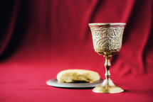 Unleavened bread, chalice of wine, silver kiddush wine cup on red background. Communion still life. Christian communion concept for reminder of Jesus sacrifice. Easter passover