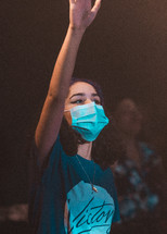 teen girl wearing a face mask with hand raised