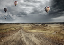 hot air balloons over a dirt road 