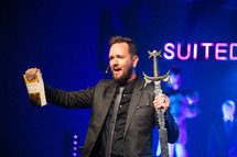 minster holding a sword and a Bible during a worship service 