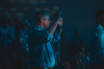 men with hands raised during a worship service 