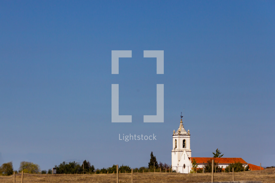 An isolated church near Conimbriga in Portugal under a cloudless blue sky
