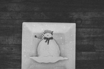 A white snowman plate on wood