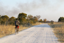 man riding a bike down a dirt road 