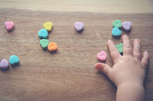 a toddler's hand touching heart shaped candy 