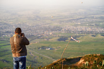 a man taking a picture of a green valley 
