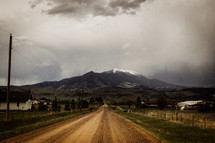 dirt road leading to a snow capped mountain peak 