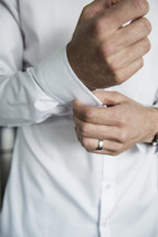 groom fastening the buttons on his shirt 