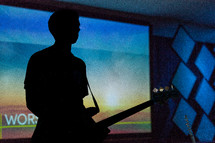silhouette of a man at the altar holding a guitar 